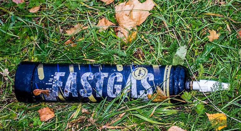 Närbild på en tub med lustgas som ligger slängd på gräset. Foto: Mostphotos.