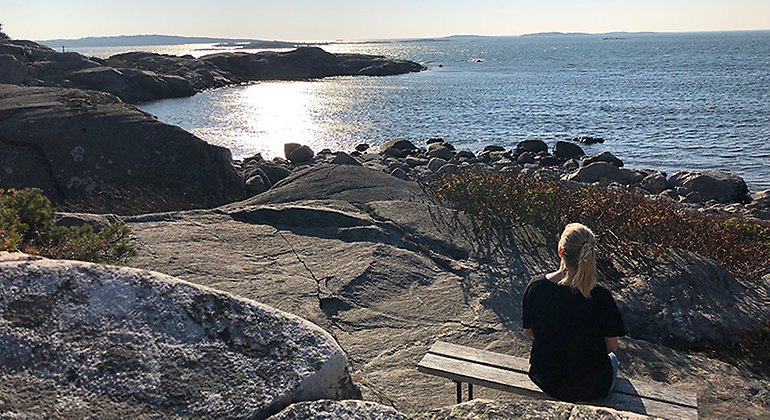 kvinna som sitter på en bänk och kollar ut över havet